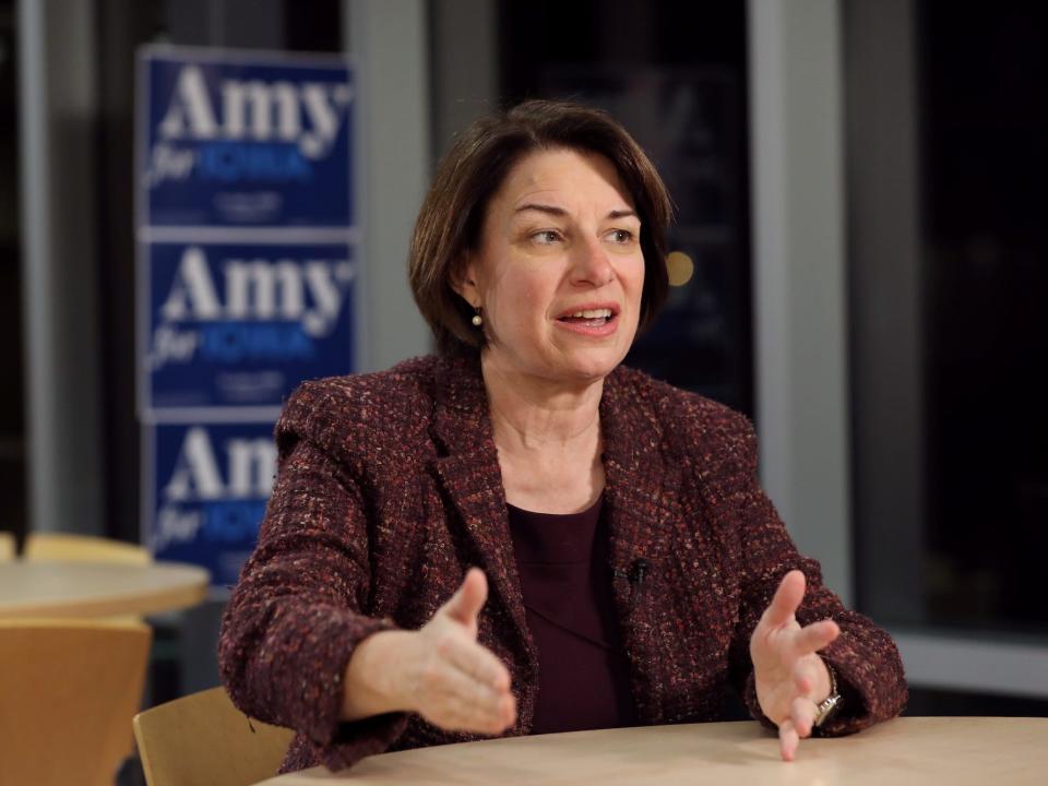 Amy Klobuchar sits at a desk and speaks during her presidential campaign