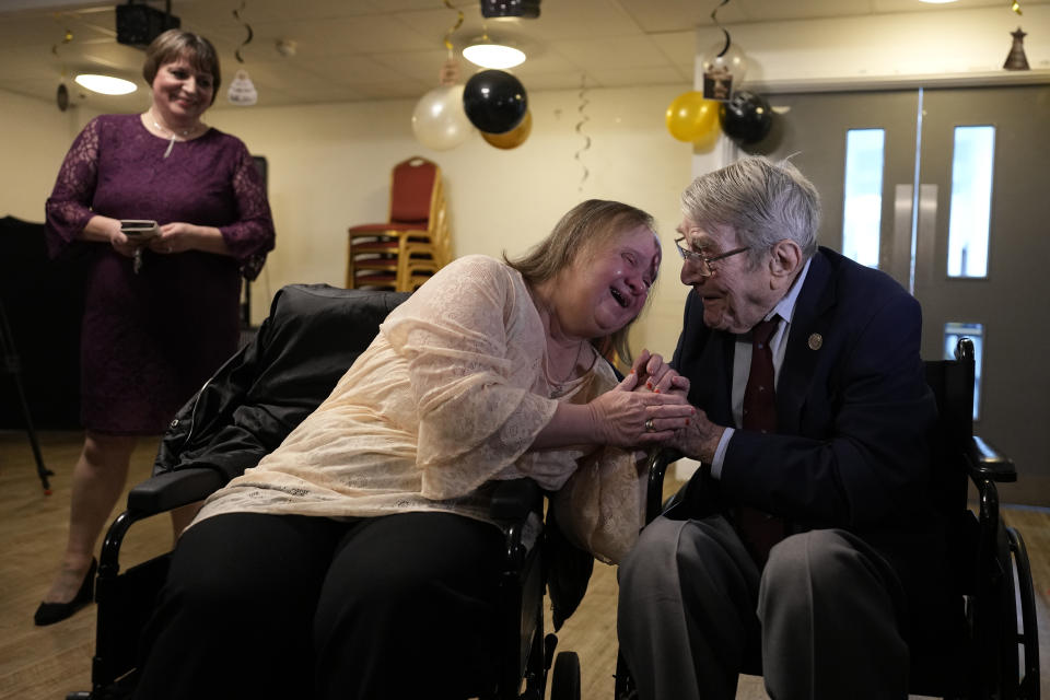 D-Day veteran Bill Gladden greets his tearful daughter Lynda, watched by his niece Kaye Thorpe at a surprise 100th birthday party in Haverhill, England, Friday, Jan. 12, 2024. Gladden spoke to the AP on the eve of his 100th birthday, and is a veteran of the 6th Airborne Armoured Reconnaissance Regiment, part of the British 6th Airborne Division, he landed by glider on the afternoon of D-day, 6th June 1944 in Normandy. Gladden was born January. 13, 1924. (AP Photo/Alastair Grant)