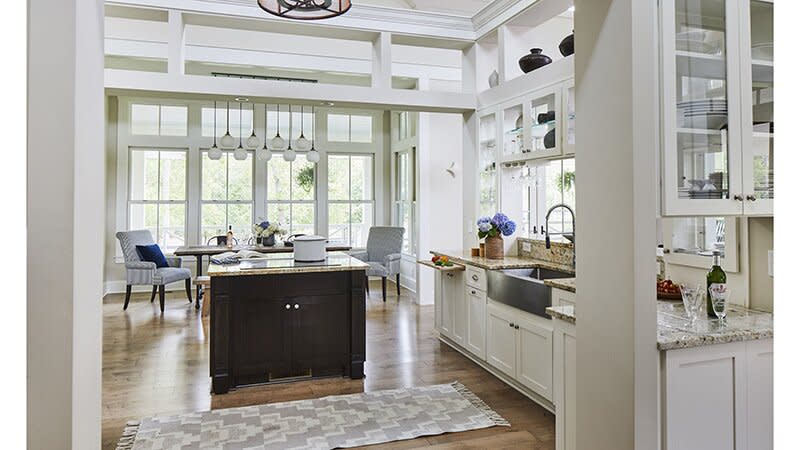 Southern Living semi open layout kitchen that has an eat in area, black kitchen island, and white cabinets