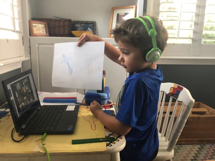 Six-year-old Ezra holds up a drawing for his first grade Zoom class.