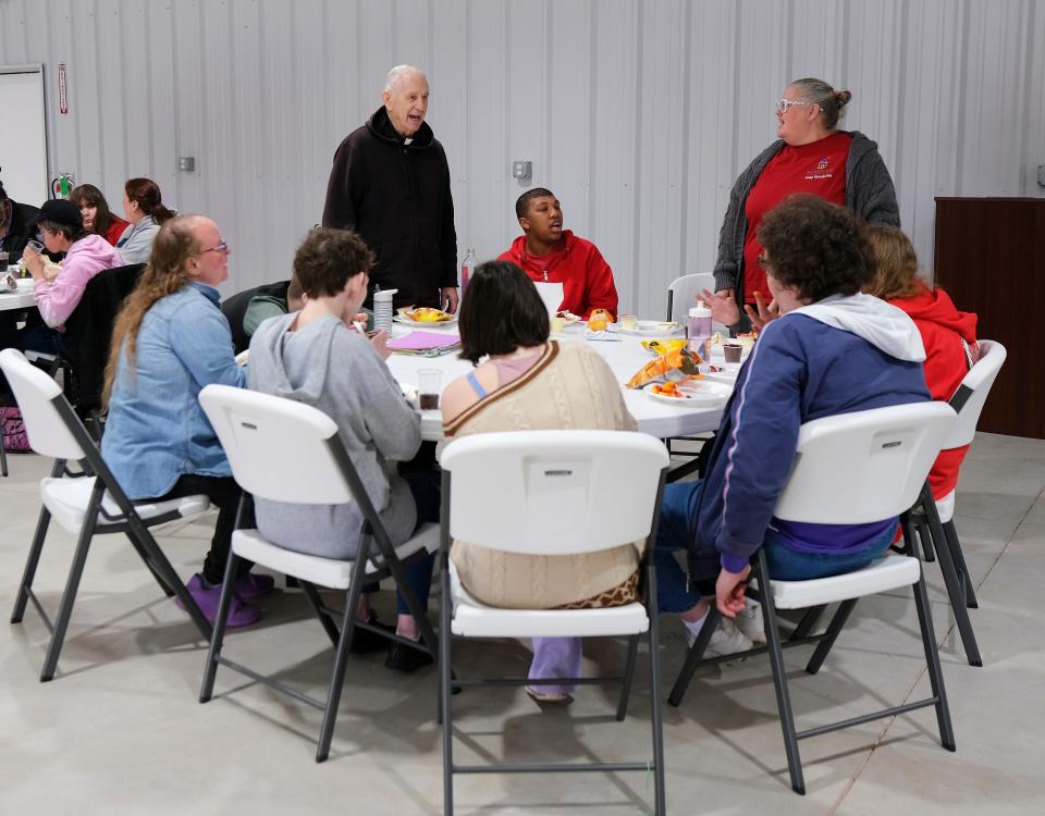 The Rev. Paul Zahler, a Benedictine monk and Catholic priest, standing at left, leads a song before lunch at a spring session of Camp Benedictine for people with special needs in McLoud.