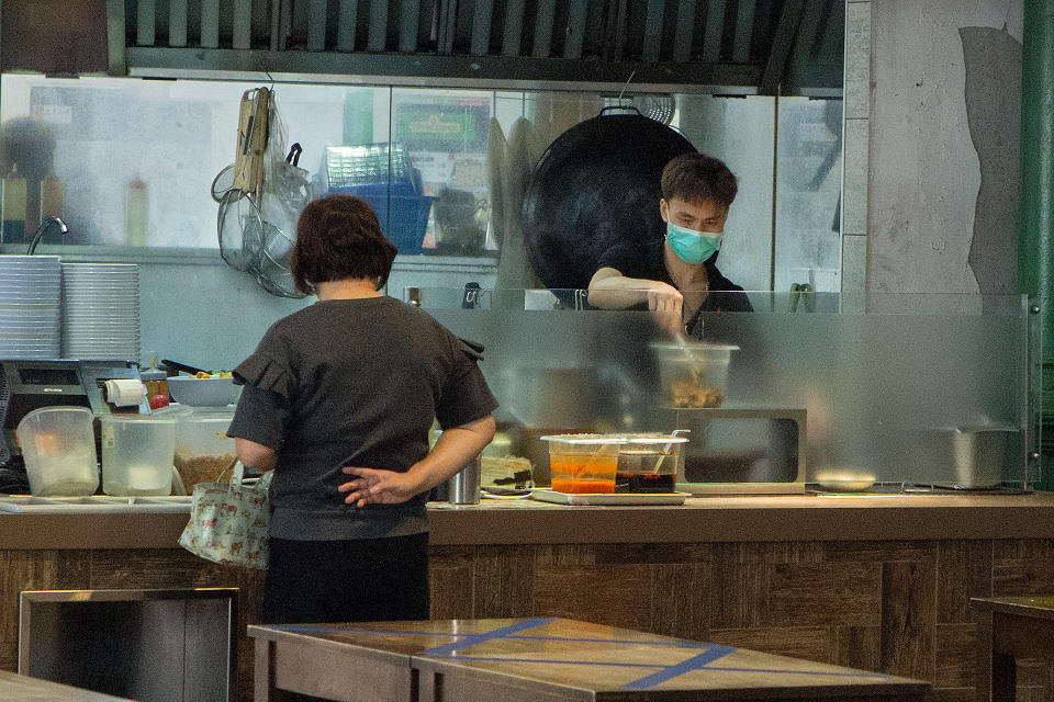 A hawker at Lau Pa Sat prepares a take-away meal for a customer on 7 April 2020, the first day of Singapore's month-long circuit breaker period. (PHOTO: Dhany Osman / Yahoo News Singapore)