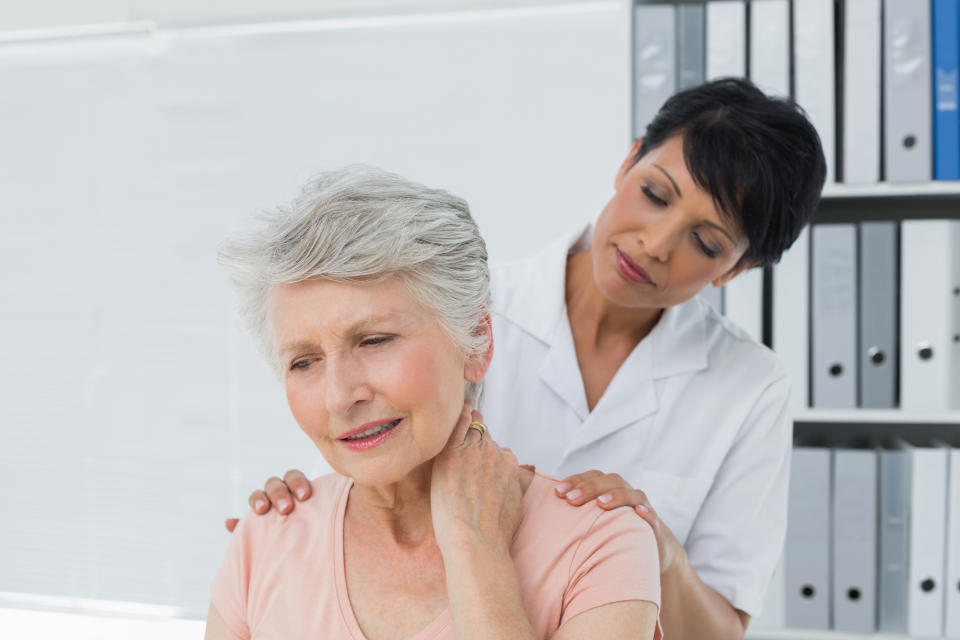 Woman in white medical coat massaging the back of an older woman rubbing her neck