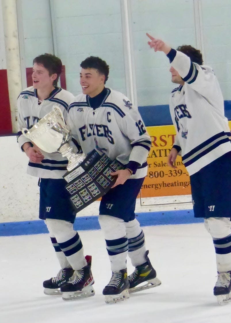 Framingham captains, from left, Robby White, Noah Albright and Jeremuy Auren carry the trophy after the Flyers defeated Burlington to win the Cahoon Cup championship Wednesday night at the Burlington Ice Palace in Burlington.