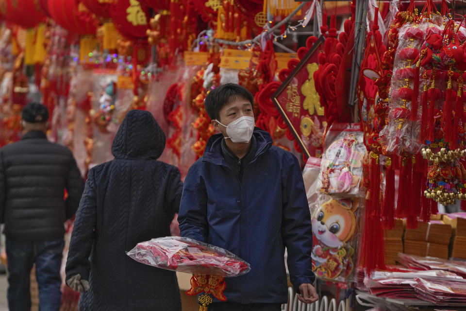 A man wearing a face mask shops for Chinese Lunar New Year decorations at a pavement stores in Beijing, Saturday, Jan. 7, 2023. China has suspended or closed the social media accounts of more than 1,000 critics of the government's policies on the COVID-19 outbreak, as the country moves to further open up. (AP Photo/Andy Wong)