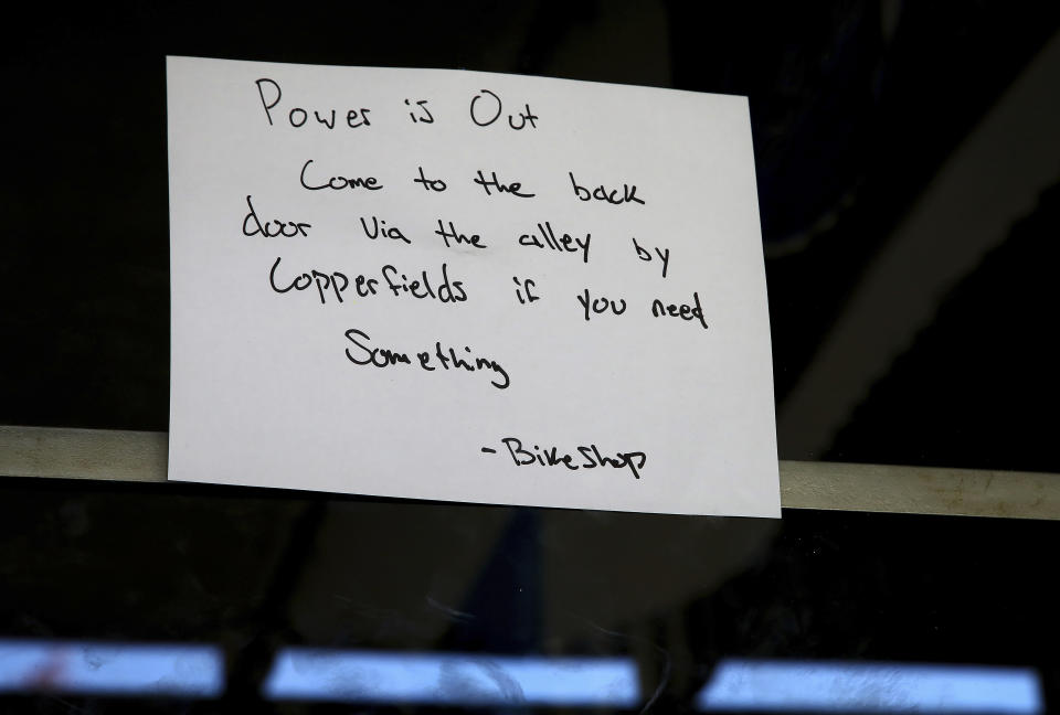 A note on the front door of the Calistoga Bike Shop instructs customers on how to enter the shop after a power outage Monday, Oct. 15, 2018, in Calistoga, Calif. Northern California's biggest utility has taken the unprecedented step of cutting electricity for tens of thousands of customers in an attempt to prevent wildfires amid rising winds and official warnings on Monday of extreme fire danger. (AP Photo/Ben Margot)