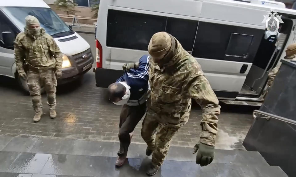 In this photo taken from video released by Investigative Committee of Russia on Sunday, March 24, 2024, a suspect in the Crocus City Hall shooting on Friday is escorted to the Russian Investigative Committee headquarters in Moscow, Russia. (Investigative Committee of Russia via AP)