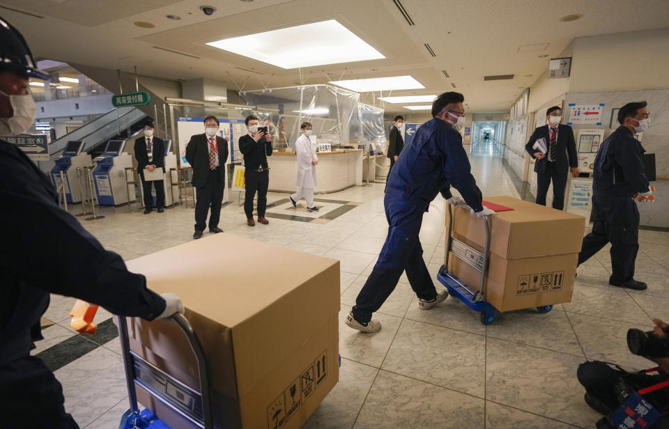 Delivery staff bring Pfizer Inc's COVID-19 vaccine to a Tokyo hospital, Japan, Tuesday, Feb. 16, 2021. Japan's COVID-19 vaccinations are scheduled to begin Wednesday after the government granted belated first approval to a shot co-developed by Pfizer Inc. (Kimimasa Mayama/Pool Photo via AP)