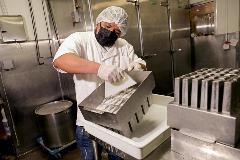 A masked and gloved man works inside an ice cream shop.