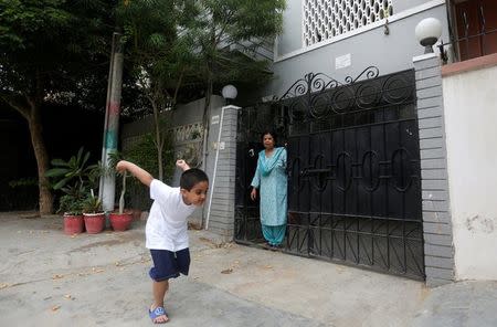 Rehana Khursheed Hashmi, 75, migrated from India with her family in 1960 and whose relatives, live in India, stands at the entrance of her house as her five year-old grandson Faraz Hashmi playing in Karachi, Pakistan August 7, 2017. REUTERS/Akhtar Soomro
