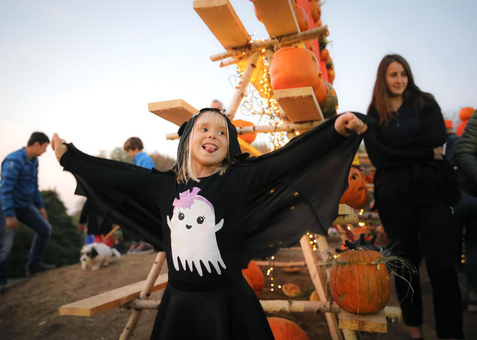 In this Sunday, Oct. 27, 2019 photo a little girl shows off her costume near Halloween pumpkins at The Halloween Pumpkin Fest in Bucharest, Romania. (AP Photo/Vadim Ghirda)