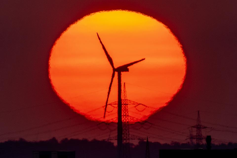 FILE - A wind turbine works in front of the rising sun in Frankfurt, Germany, May 9, 2022. Germany is shutting down its last three nuclear power plants on Saturday, April 15, 2023, as part of an energy transition agreed by successive governments and the price of installing solar and wind energy has dropped significantly in recent years. (AP Photo/Michael Probst, File)