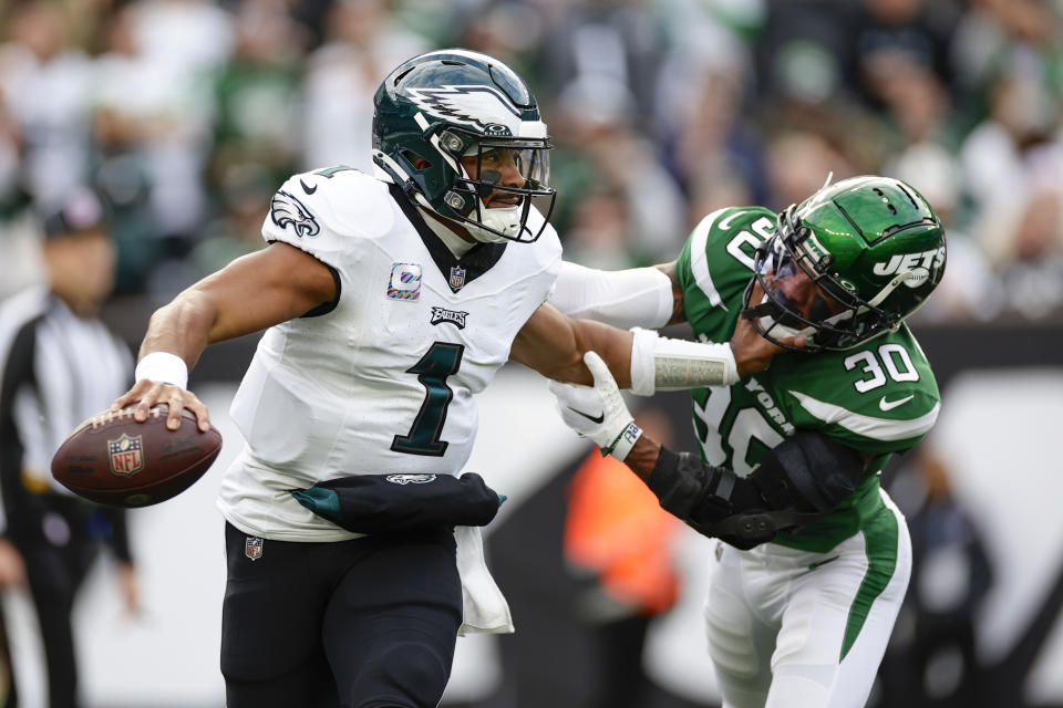 Philadelphia Eagles quarterback Jalen Hurts, left, fends off New York Jets' Michael Carter II as he looks to throw during the first half of an NFL football game, Sunday, Oct. 15, 2023, in East Rutherford, N.J. (AP Photo/Adam Hunger)