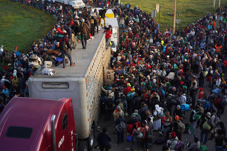 Migrants, part of a caravan of thousands traveling from Central America en route to the United States, try to catch a ride on a truck, in Irapuato, Mexico November 12, 2018. REUTERS/Go Nakamura