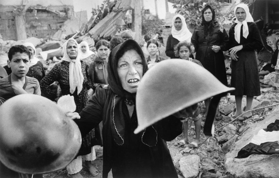 FILE - A Palestinian woman brandishes helmets during a memorial service for victims of Lebanon's Sabra refugee camp massacre in Beirut, Lebanon, Sept. 27, 1982. She said the helmets were worn by those who massacred hundreds of Palestinians. (AP Photo/Bill Foley, File)