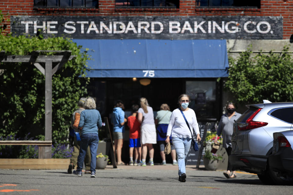 FILE - In this June 16, 2020, file photo, The Standard Baking Company serves customers at their door front in Portland, Maine. The number of deaths per day from the coronavirus in the U.S. has fallen in recent weeks to the lowest level since late March, even as states increasingly reopen for business. But scientists are deeply afraid the trend may be about to reverse itself. (AP Photo/Robert F. Bukaty, File)