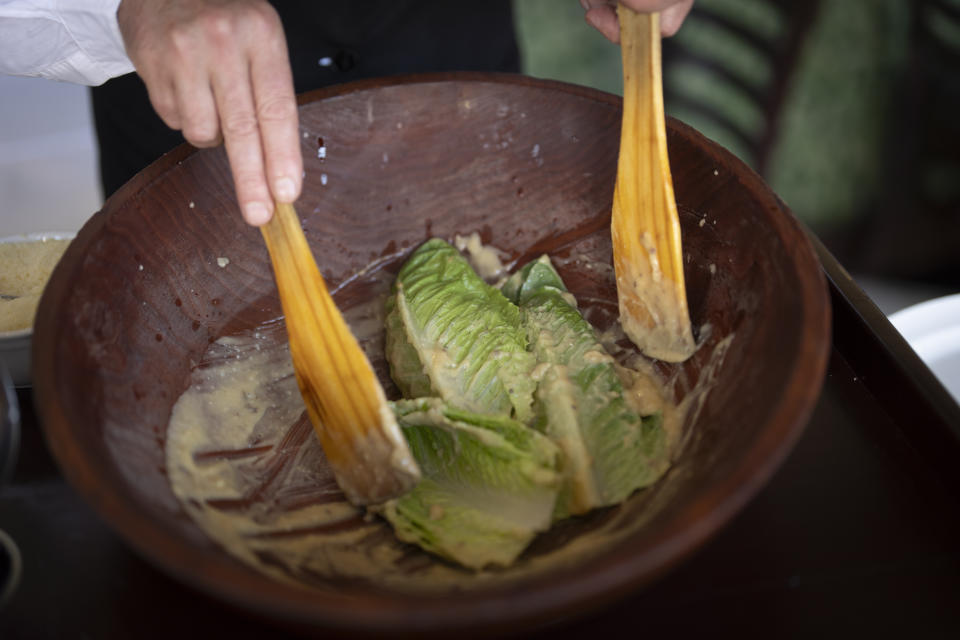 Salad Master Efrain Montoya mixes Romaine leaves with other ingredients as he prepares a Caesar salad at Ceasar's restaurant Thursday, June 27, 2024, in Tijuana, Mexico. Caesar salad has something to celebrate: It's turning 100. Italian immigrant Caesar Cardini is said to have invented the dish on July 4, 1924, at his restaurant, Caesar's Place, in Tijuana, Mexico. (AP Photo/Gregory Bull)