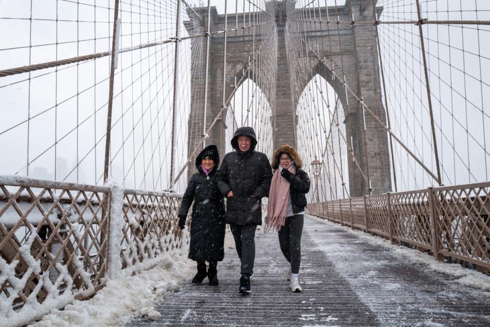 People walk across the Brooklyn Bridge in the blowing snow in Manhattan as a large winter storm makes its way across the area (Getty Images)