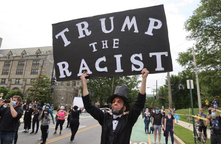 A man dressed as Abraham Lincoln holds up a sign as Donald Trump&#x002019;s motorcade passes in Washington in June.