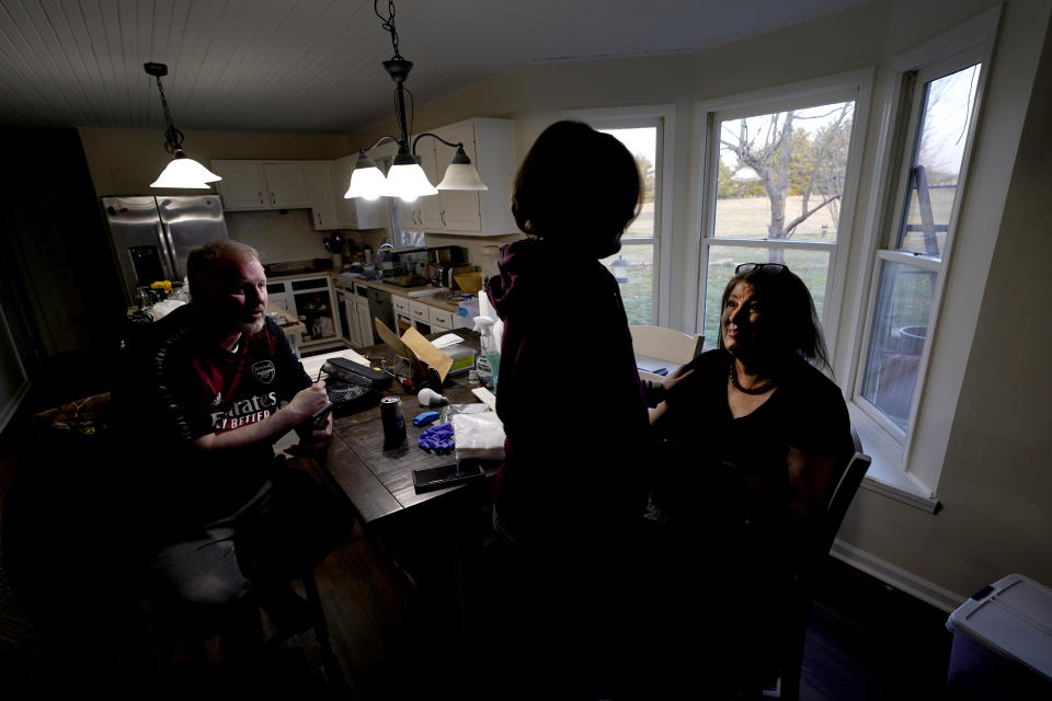 Kari Wegg, right, smiles at her oldest son, Gavin, during a conversation with him and husband Rodney, at the kitchen table of their Westfield, Ind., home on Sunday, March 21, 2021. (AP Photo/Charles Rex Arbogast)