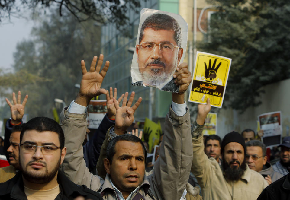 FILE - In this file photo taken Friday, Dec. 20, 2013, supporters of Egypt's ousted President Mohammed Morsi hold his poster as they raise their hands with four fingers, which has become a symbol for Morsi supporters, during a protest in Cairo, Egypt. While last week's constitutional referendum approved the draft charter, the low turnout - less than 39 percent - has put on display the country's enduring divisions six months after the ouster of Morsi and nearly three years after autocrat Hosni Mubarak was overthrown. (AP Photo/Amr Nabil, File)