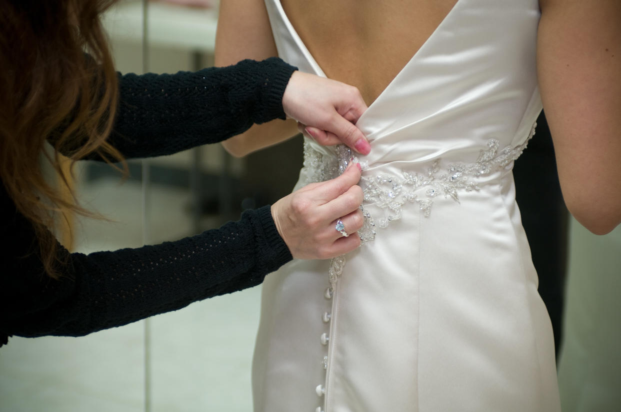 A bride getting ready before wedding. She is having help with her dress. 