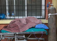 A COVID-19 patient covered under a blanket receives oxygen outside an emergency ward as she waits for a bed to be allotted at a hospital in Kathmandu, Nepal, Thursday, May 6, 2021. Nepal's main cities and towns including the capital Kathmandu has been in lockdown since last month as the number coronavirus cases and deaths continue to rise. (AP Photo/Niranjan Shrestha)