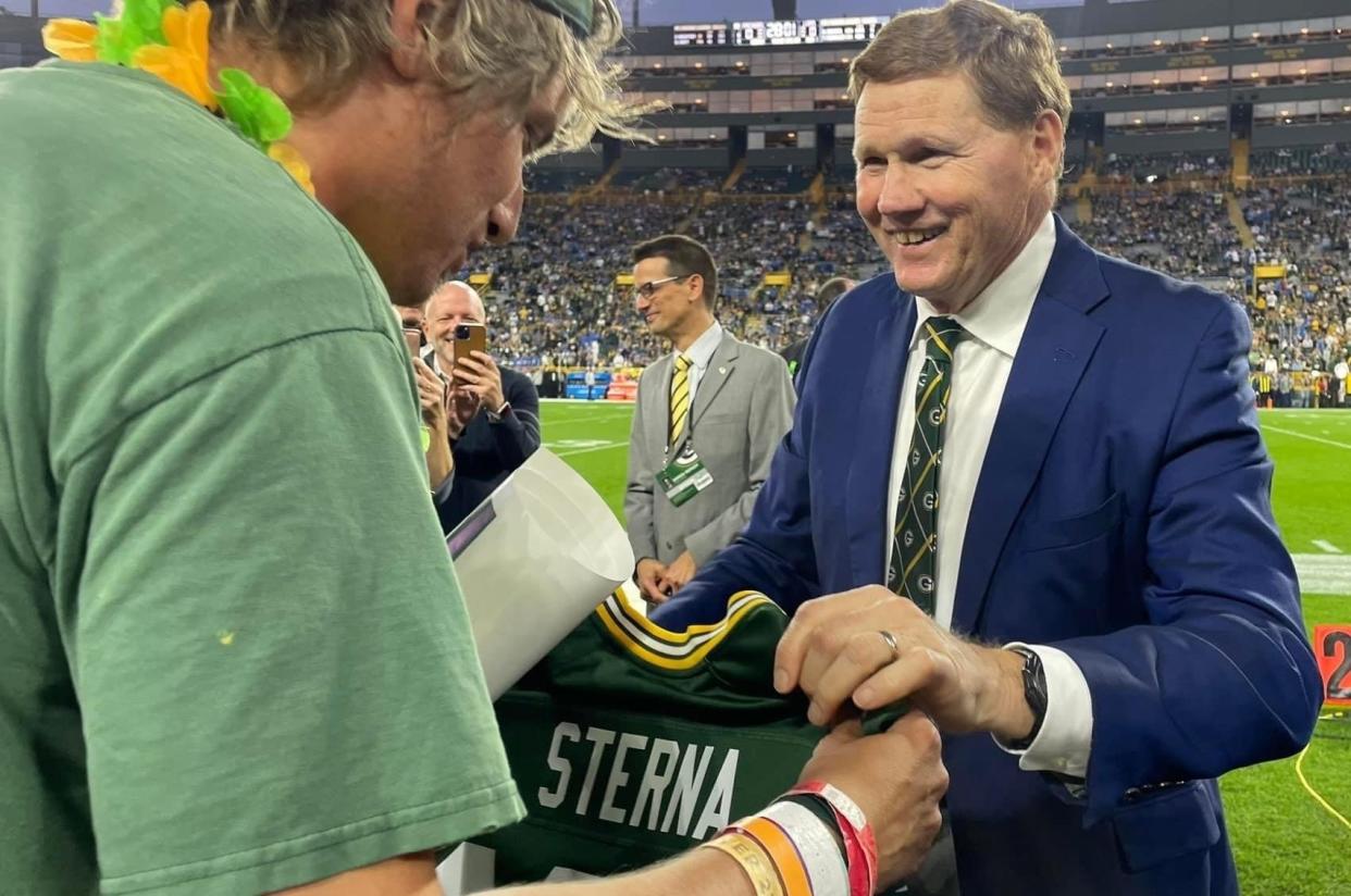 Justin Sterna of Mequon receives a jersey with his name and the number 100 on it for attending 100 consecutive Green Bay Packers games from Packers President and CEO Mark Murphy before a game against the Detroit Lions on Sept. 28 at Lambeau Field in Green Bay.