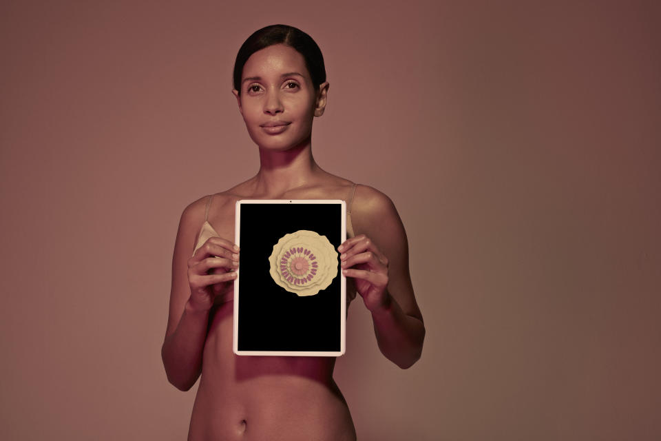 Female holding tablet in front of body to display coloured x-ray illustrations made out of hand made paper structures