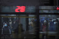 In this Jan. 14, 2019, photo, a bus passes by pedestrians at a traffic intersection in the Central Business District in Beijing. China's slowing economy is squeezing the urban workers and entrepreneurs the ruling Communist Party is counting on to help transform this country from a low-wage factory floor into a prosperous consumer market. (AP Photo/Andy Wong)