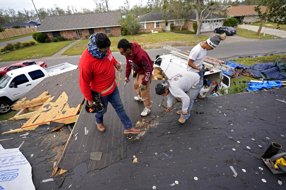 Roofers work on the heavily damaged and gutted home of Christi and Brandy Monticello, in the aftermath of Hurricane Laura and Hurricane Delta, in Lake Charles, La., Friday, Dec. 4, 2020. (AP Photo/Gerald Herbert)