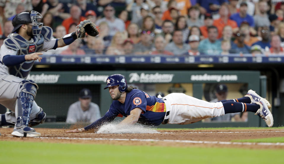 Seattle Mariners catcher Omar Narvaez, left, waits for the ball as Houston Astros' Jake Marisnick, right, dives safely for the plate on the sacrifice fly by Josh Reddick during the seventh inning of a baseball game Sunday, Aug. 4, 2019, in Houston. (AP Photo/Michael Wyke)