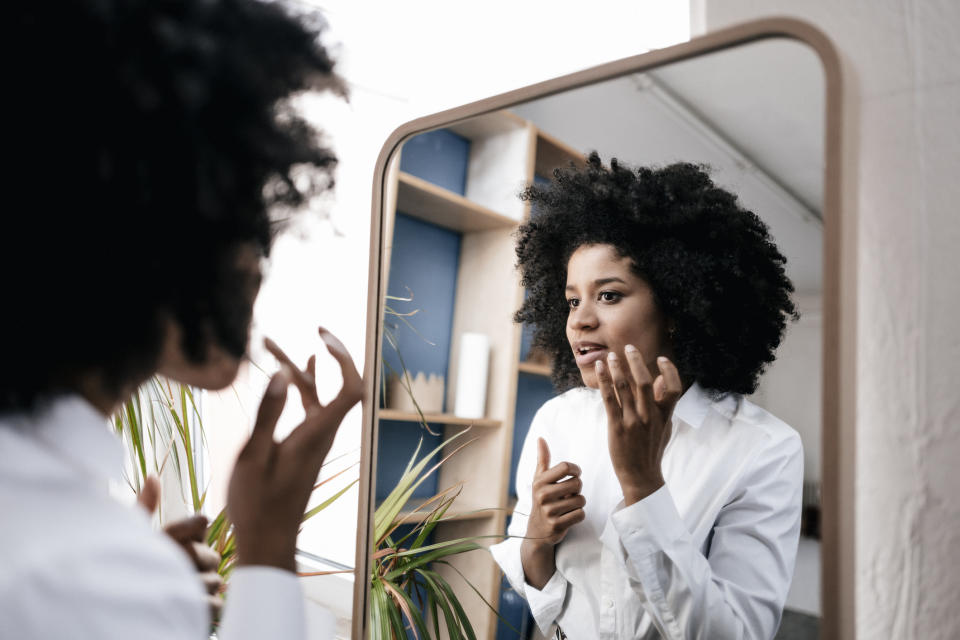 A woman applying makeup in the mirror