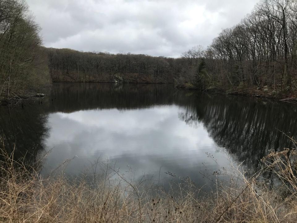 The Manton Reservoir, which was created to hold water for downstream mills, flows under a dam to form the Moshassuck River.