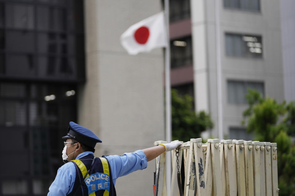 A police officer stands guard outside of a police station with the national flag at half-staff on the day of former Prime Minister Shinzo Abe's funeral in Tokyo, Tuesday, Sept. 27, 2022. He was assassinated in July. (AP Photo/Hiro Komae)