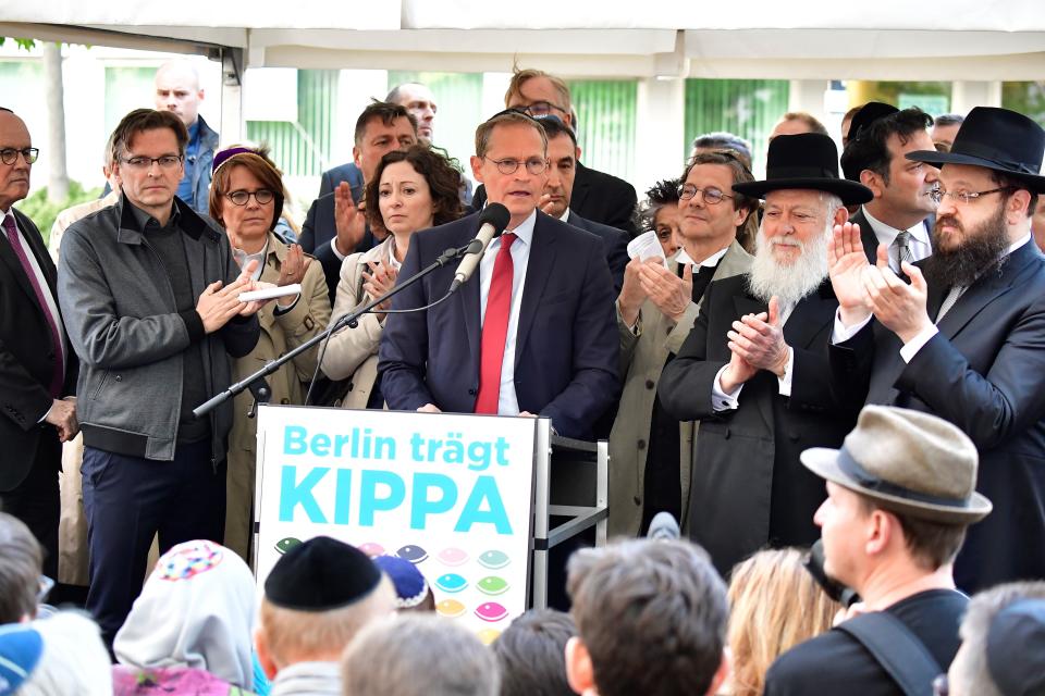 Berlin's mayor Michael Mueller (C) is applauded by Rabbis Yitshak Ehrenberg (2ndR) and Yehuda Teichtal (R) during the event.