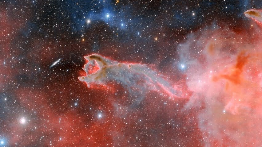  An image of  the God's Hand cometary globule. The image features pink and blue clouds against a starry background.  One of the clouds is in the shape of a claw or hand. 