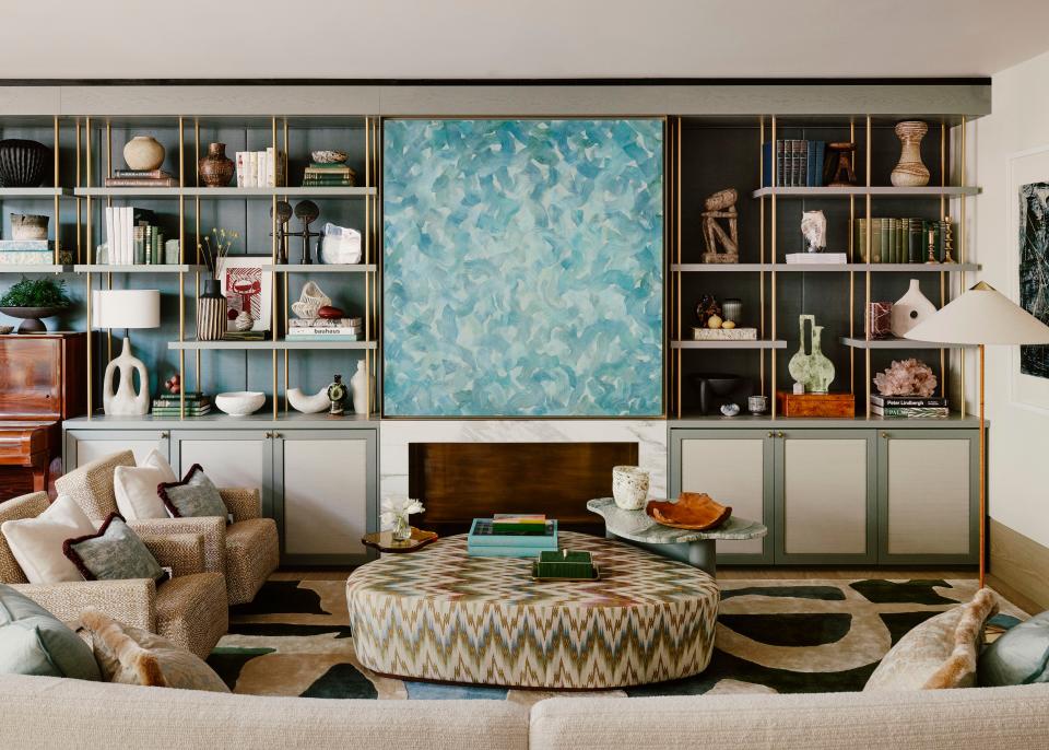 Displaying objets d’art—including linocuts, ceramic lighting, vintage vases, books, crystals, and tribal sculptures—across the shelving adds visual interest and creates a dynamic focal point for the open-plan living room. At its center is a painting by British artist Abhayavajra Newman, which also cleverly hides the television. The custom wool rug is by Christopher Farr and the ottoman is upholstered in Teyssier’s Firenze flame stitch linen.