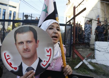 A woman holds up a picture of Syria's President Bashar al-Assad while carrying a Syrian flag during a sit-in organised by activists near the U.S. embassy in Awkar, north of Beirut, against potential REUTERS/Mohamed Azakir