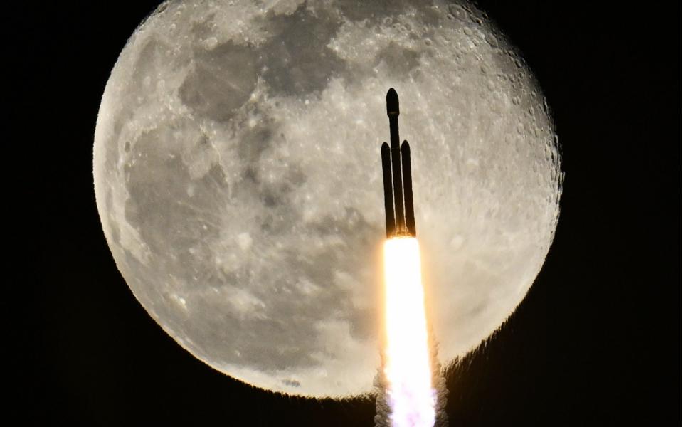 A SpaceX Falcon Heavy rocket passes in front of the moon as it launches the X37B at the Kennedy Space Center, Florida on Thursday