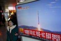 A passenger walks past a TV screen broadcasting a news report on North Korea's long range rocket launch at a railway station in Seoul, South Korea, February 7, 2016. REUTERS/Kim Hong-Ji