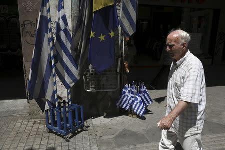 A man walks past Greek national flags and European Union flags on display outside a shop in central Athens, Greece July 24, 2015. REUTERS/Yiannis Kourtoglou