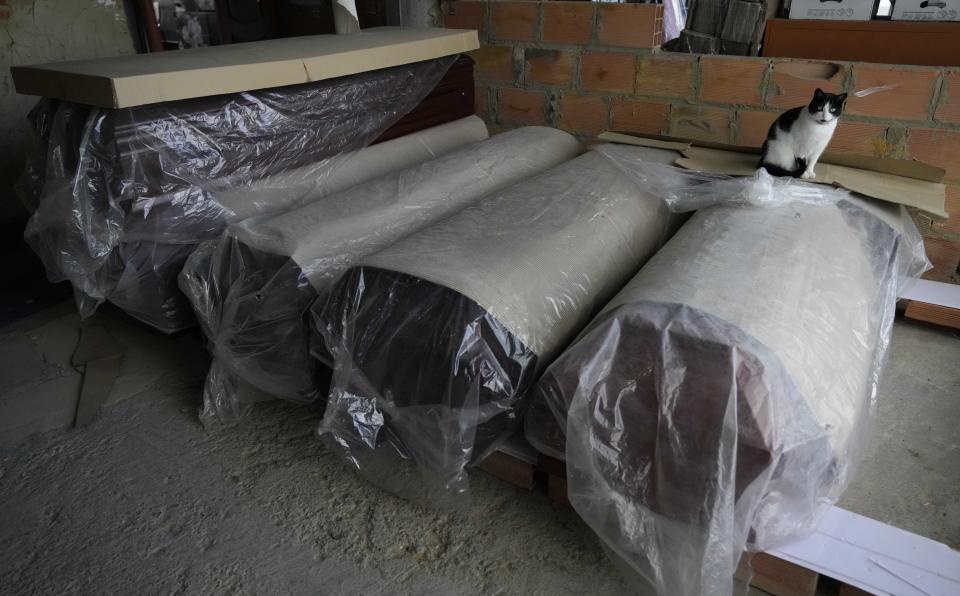 A cat sits on a new coffin in a storage area of the Zipaquira's Park Cemetery in Zipaquira, Colombia, Friday, June 18, 2021. Funeral workers in Colombia are struggling to dispose of bodies as the country experiences a surge in deaths from COVID-19. (AP Photo/Fernando Vergara)