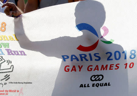 A man displays a banner as he participates at the international Rainbow Memorial Run during the inauguration of the Gay Games village at the Hotel de Ville city hall in Paris, France, August 4, 2018. REUTERS/Regis Duvignau