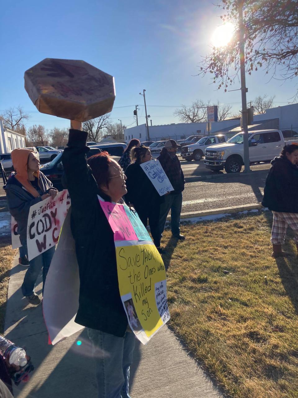 Frances Weeks-Combs raises a drum and wears signs, calling for justice for her son Cody Weeks Combs.