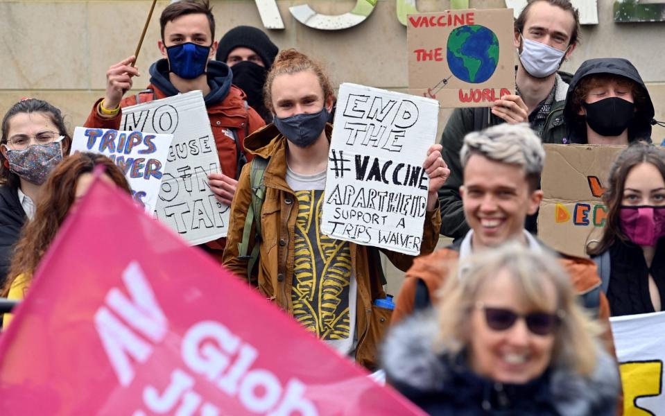 Demonstrators hold placards and wave flags as they protest outside the offices pharmaceutical company AstraZeneca - PAUL ELLIS/AFP