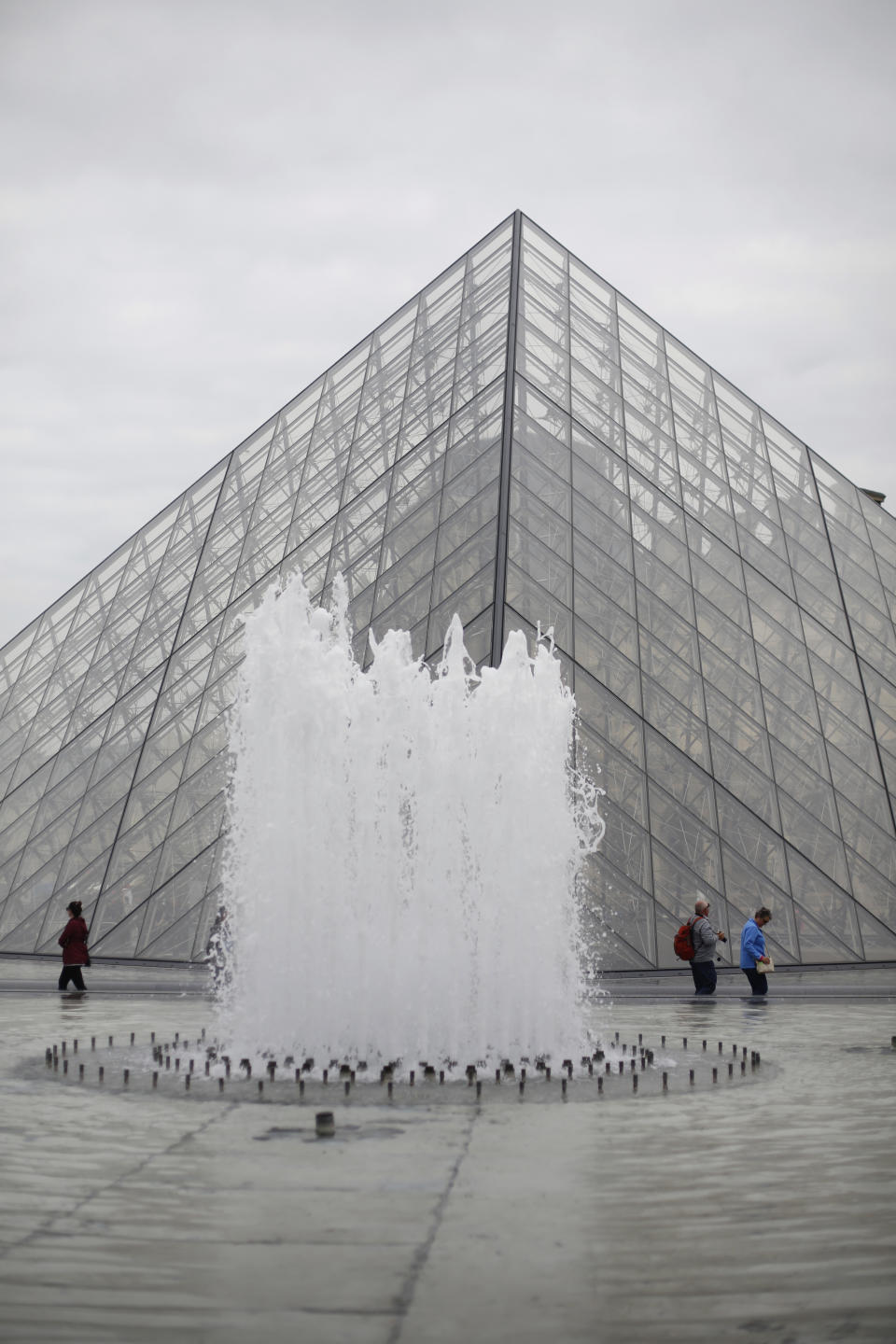 Tourists walk at the bottom of the pyramide of the Louvre museum, in Paris, Friday, May 17, 2019. Paris' Louvre museum is paying tribute to the architect of its giant glass pyramid, I.M. Pei, who has died at age 102. (AP Photo/Thibault Camus)