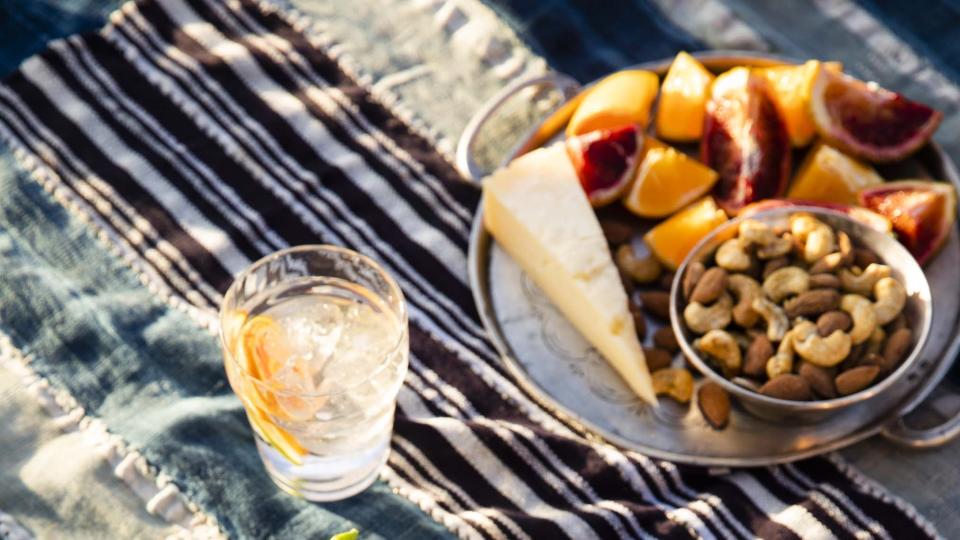 crispy brussels sprouts salad in a bowl on a tablecloth with cheese and fruit and nuts near by