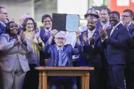 Wisconsin Gov. Tony Evers holds up Assembly Bill 438 and Assembly Bill 439 after signing them at American Family Field Tuesday, Dec. 5, 2023, in Milwaukee. The bills use public funds to help the Milwaukee Brewers repair their stadium over the next three decades. (AP Photo/Morry Gash)