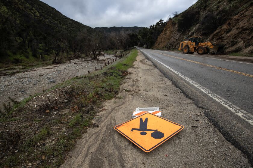 Lake Hughes, CA - March 30: A loader moves rocks and mud along Lake Hughes Road, where closures persist on Thursday, March 30, 2023 in Lake Hughes, CA. (Brian van der Brug / Los Angeles Times)